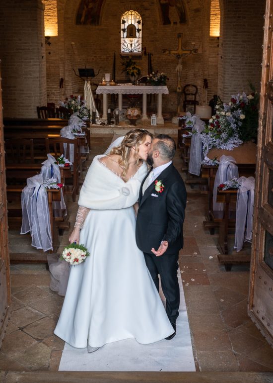 sposi che si baciano in chiesa sulla navata