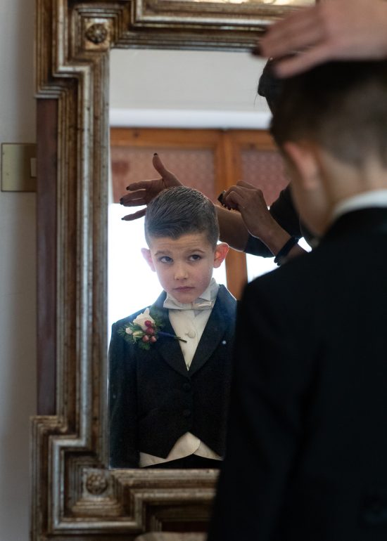 bambino che viene pettinato davanti allo specchio nel momento dei preparativi