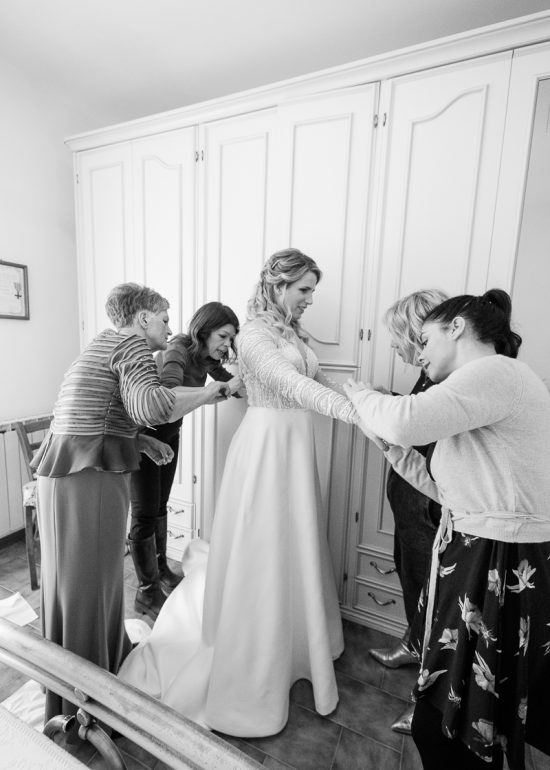 le donne di casa che aiutano la sposa a vestirsi