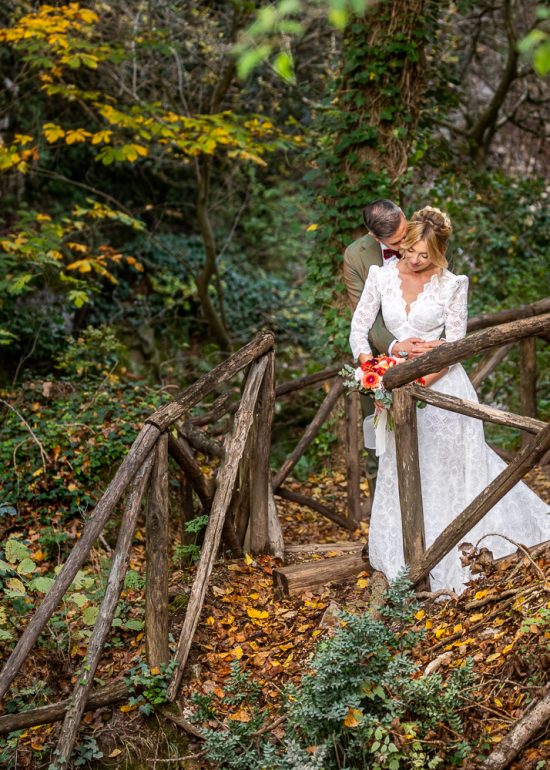 sposo che bacia la sposa dietro la staccionata nel bosco